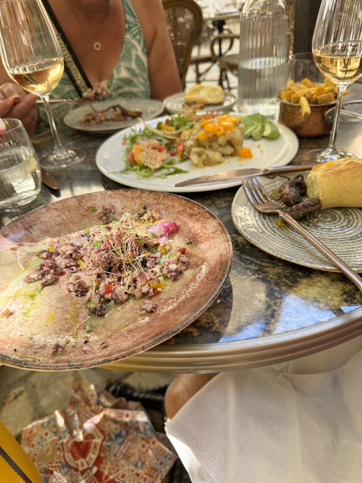Carpaccio de poulpe avec légumes colorés et pousses fraîches sur assiette rose