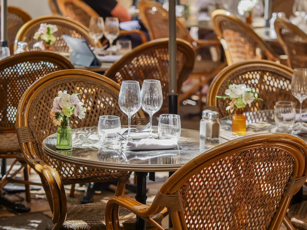 Terrasse élégante avec fauteuils en rotin et tables en marbre, décoration florale